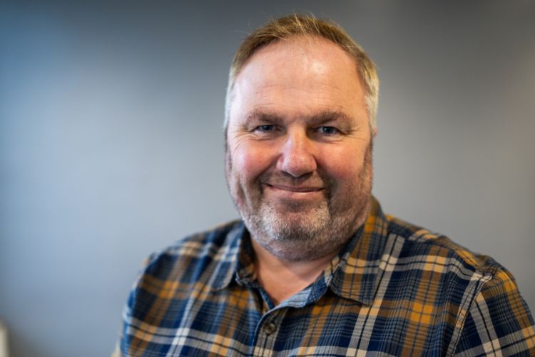 A person in a checked shirt (Mike Slade) is smiling at the camera